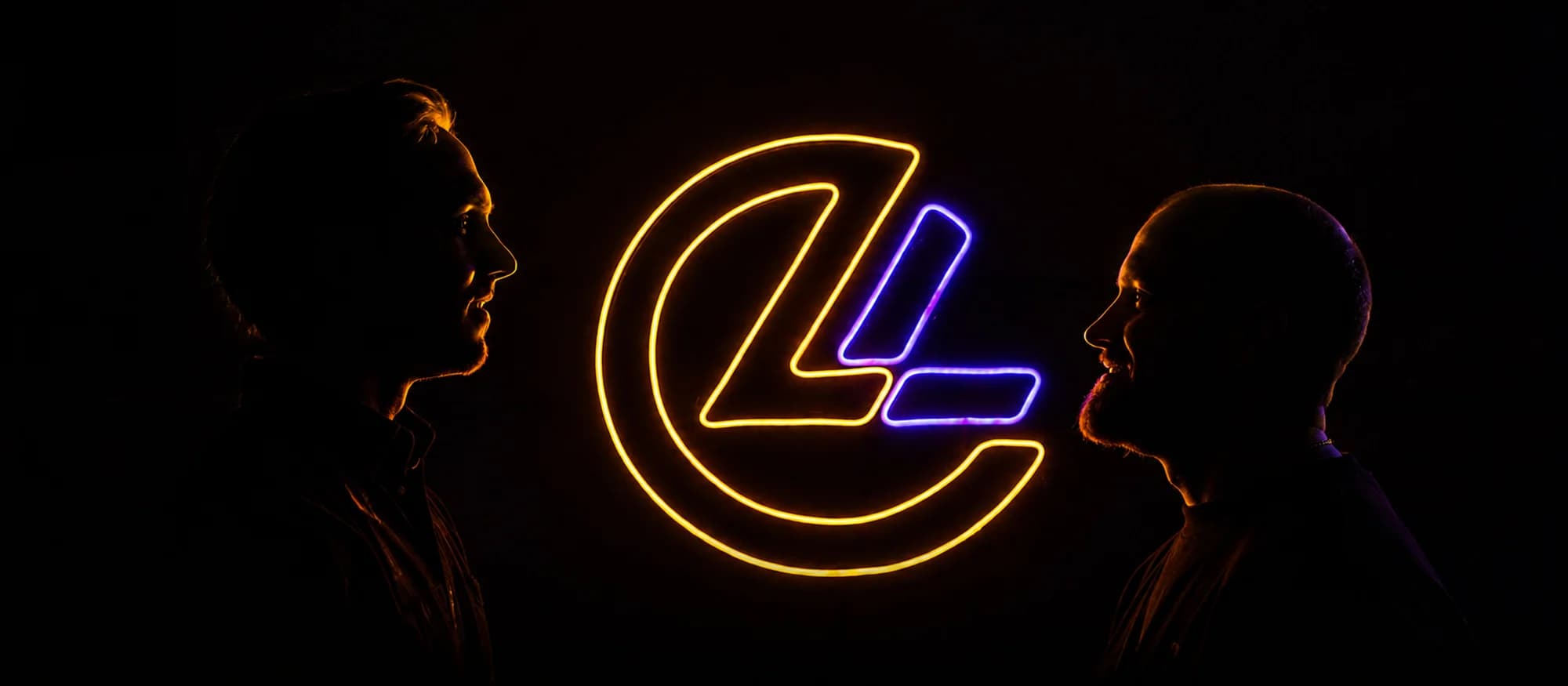Luca van Selm en Luuk van Amelsfort, de oprichters van Living Lumen, in silhouet bij hun verlichte logo.