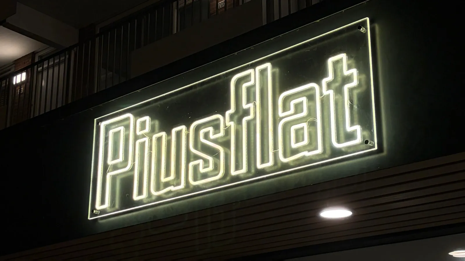 Verlicht LED-neon gevelbord Piusflat op een appartementencomplex