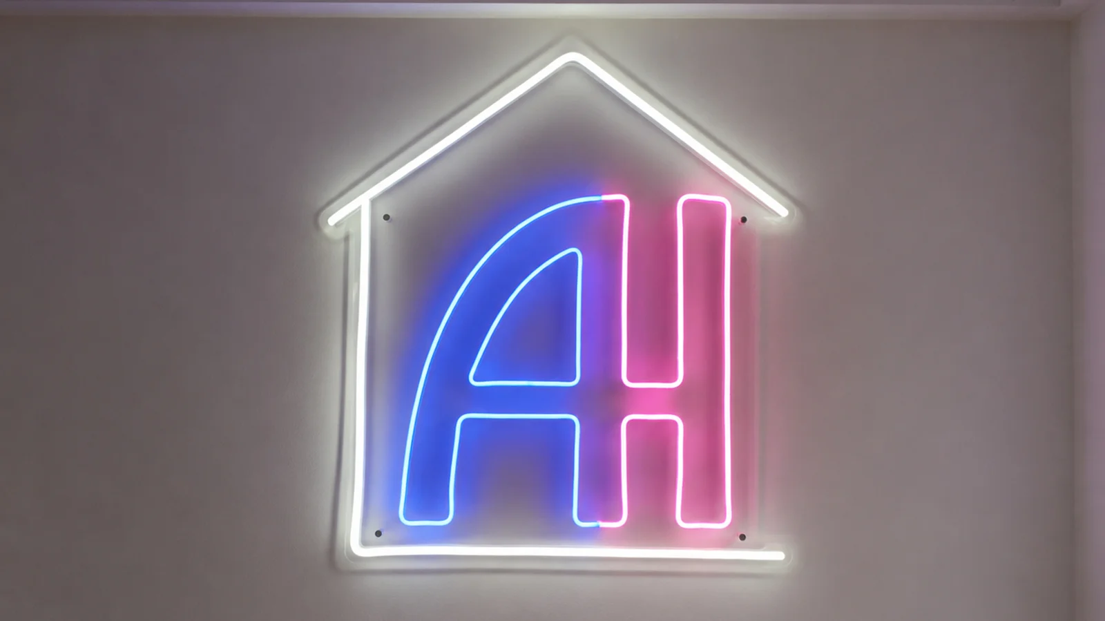 Huisvormig LED-neon logo met de letters A en H aan een kantoormuur