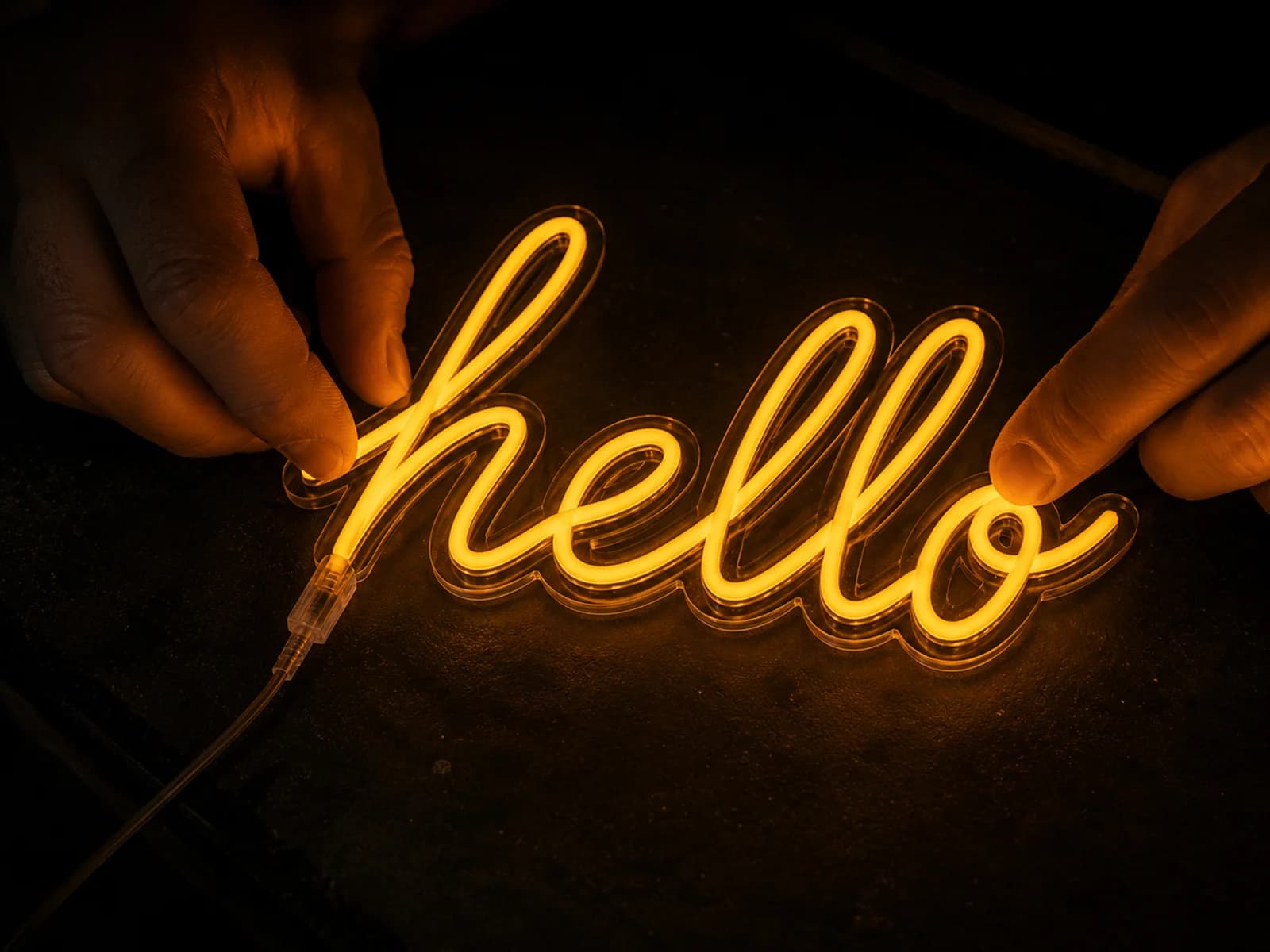 Macro van twee handen die warm gloeiende LED Neon Flex in een gefreesde gleuf in acrylaat buigen.
